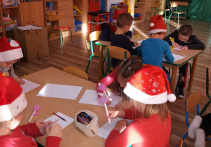 Dzieci rysują otrzymanym długopisem podziekowania dla Mikołaja